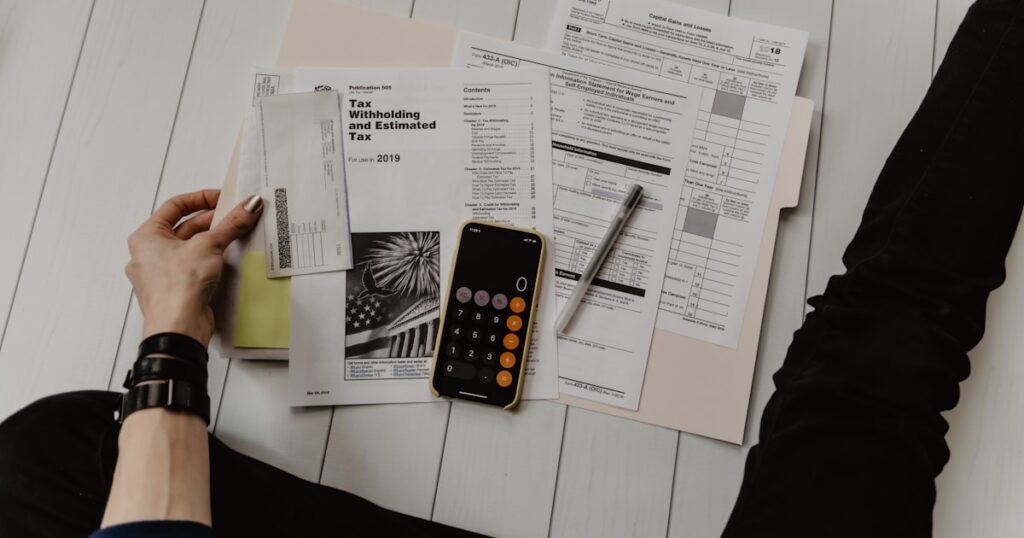 Escritorio de pyme con ordenador portátil, calculadora, factura de hosting y libreta con números — desglose del coste real de una web WordPress