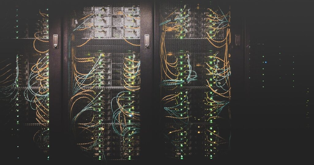 Primer plano de rack de servidores en datacenter con algunos LEDs ámbar de aviso entre luces azules de estado normal — metáfora de problemas SMTP silenciosos