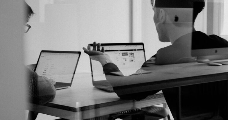 Dos personas trabajando en portátiles con paneles CRM