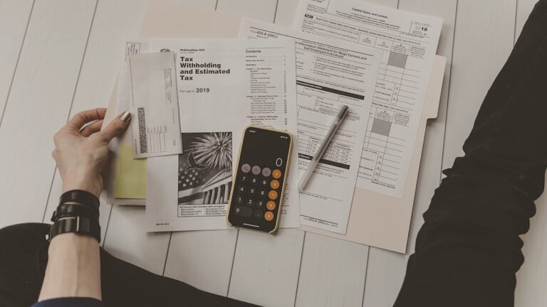 Escritorio de pyme con ordenador portátil, calculadora, factura de hosting y libreta con números — desglose del coste real de una web WordPress