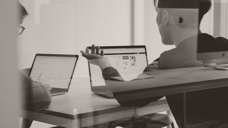 Dos personas trabajando en portátiles con paneles CRM