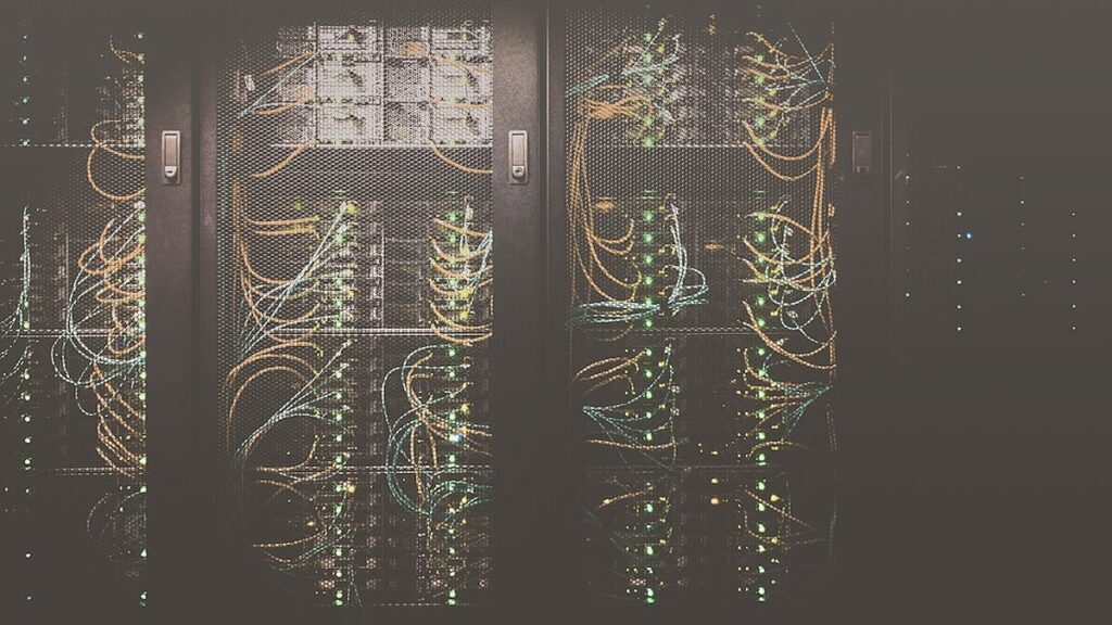 Primer plano de rack de servidores en datacenter con algunos LEDs ámbar de aviso entre luces azules de estado normal — metáfora de problemas SMTP silenciosos